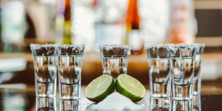Two Shots Of Tequila With Lime And Salt On A Wooden Table Bar On